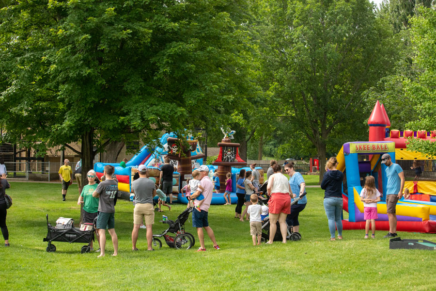 families with their kids talking around multiple inflatable attractions for kids